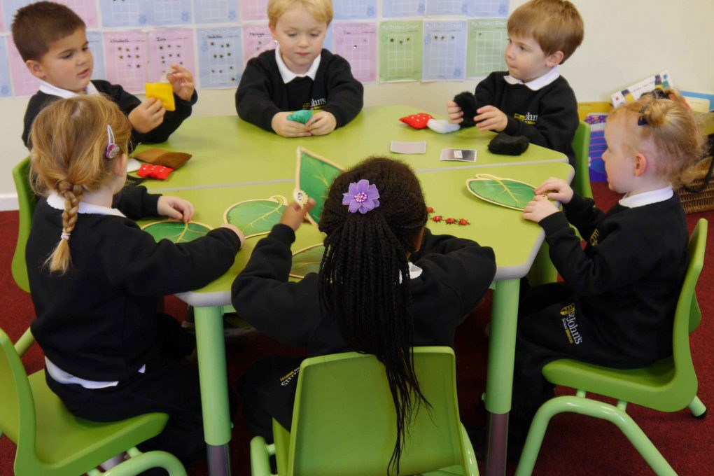 group of young children sitting around a green table at school